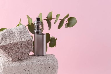 Vaping device on stone with eucalyptus branch. Modern still life, product photo. Aesthetic minimalist composition.