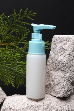 Beauty concept. Cream bottle on stone with sprig of fir on black background. Minimal still life. Product photo