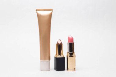 Foundation with tubes of lipstick on a white background. Beauty and fashion concept.