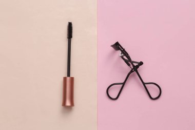 Mascara fırçası, pembe arka planda profesyonel kirpik bigudisi. Düz yatıyordu
