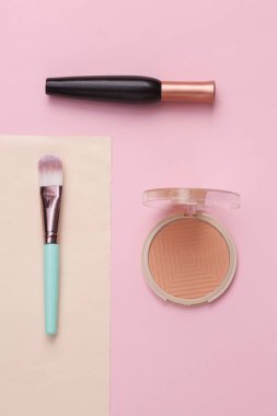 Minimum güzellik kompozisyonu. Makyaj fırçası, pudra kutusu ve rimel. Üst görünüm