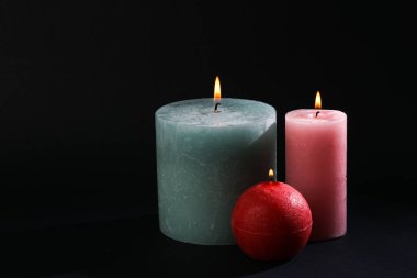 Siyah arka planda yanan mumlar.