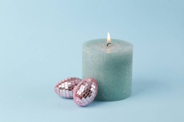 Yanan mum ve mavi arka planda Paskalya aynası yumurtaları.