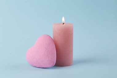 Mavi arka planda kalbi olan yanan bir mum. Pastel renk eğilimi. Romantik konsept