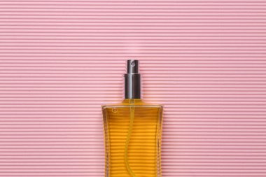 Pembe arka planda sarı parfüm şişesi