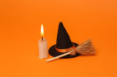 Cadılar Bayramı, turuncu arka planda süpürge ve mum olan cadı şapkası.