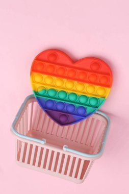 Pembe arka planda kalp şeklinde stres önleyici oyuncakla alışveriş sepeti.