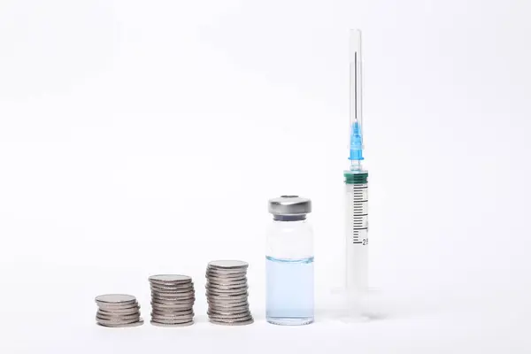 白い背景に隔離されたワクチンボトルとコインのスタックのシリンジ — ストック写真