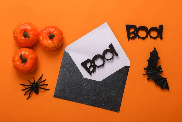 Halloween black envelope with words boo! and halloween decor on orange background. Creative layout. Top view. Flat lay