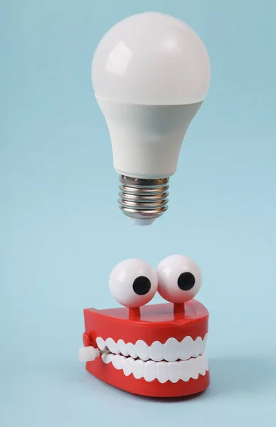 Funny toy clockwork jumping teeth with eyes and light bulb on blue background. I have an idea!