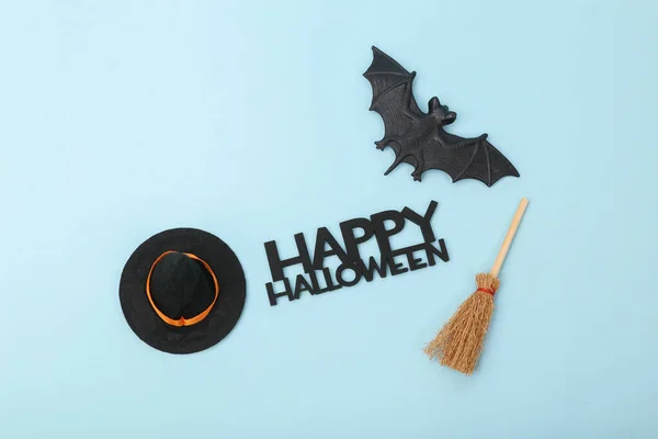 Halloween decor. Witch hat with broom and bats, word happy halloween on blue background