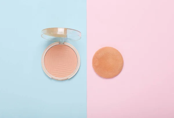 Make-up powder on a blue-pink background. Top view