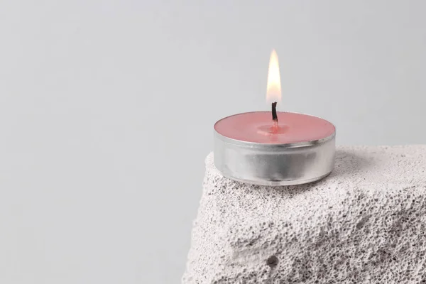 Minimalistic still life of flaming candle on a stone