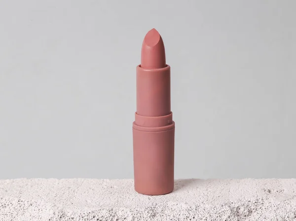 Natural cosmetic. Beauty products. Lipstick tube on stone podium, gray background. Product photo. Abstract composition. Natural showcase