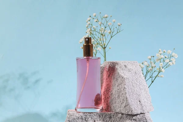 Beauty products. Perfume bottle on stones, blue background. Product photo. Abstract natural composition