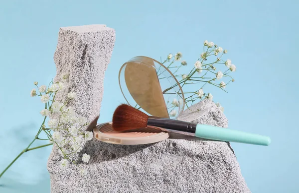Beauty products. Powder box with makeup brush on stone, blue background. Product photo. Abstract natural composition