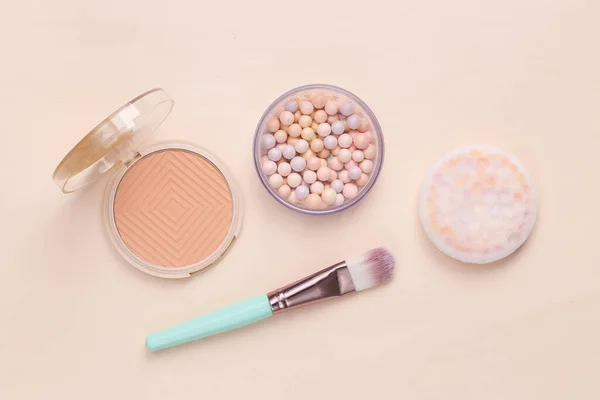 Beauty still life. Cosmetics. Powder box, powder balls with makeup brush on a beige backgroun