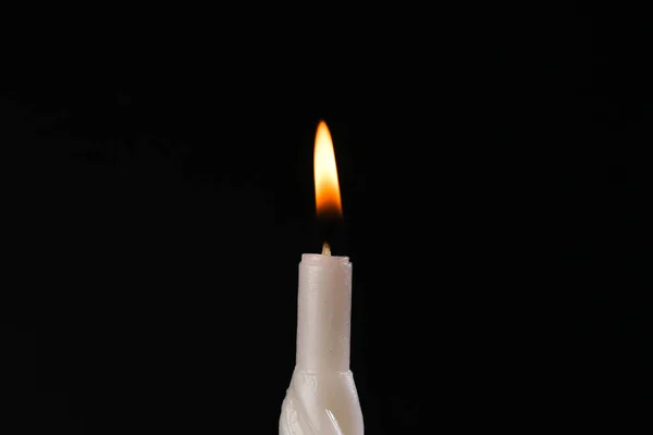 Flaming wax candle on a black background