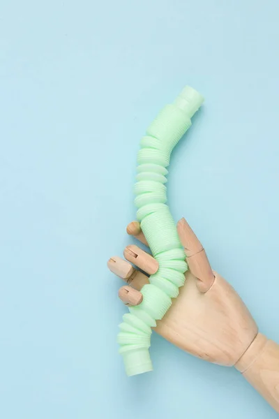 Puppet hand holding Pop tube, Sensory anti-stress toy on blue background