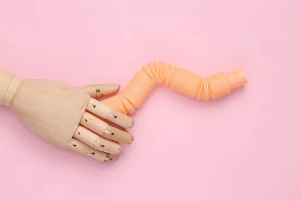Puppet hand holding Pop tube, Sensory anti-stress toy on pink background