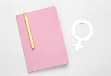 Feminizm. Pembe kapaklı kadın günlük planlamacısı ve gri arka planda Venüs kadın cinsiyet sembolü. Üst görünüm