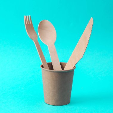 Ahşap bıçak, kaşık ve çatal mavi arka planda kağıt bardakta. Eko ürünleri