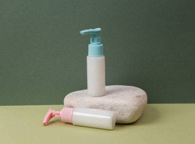 Estetik güzellik hala hayattadır. Bir şişe krema ya da taşın üzerine sıvı sabun, iki ton yeşil arka plan.