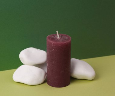 Estetik natürmort. En az olay yeri. İki tonluk yeşil zemin üzerinde çakıl taşı taşları olan balmumu aromalı mum. Aromaterapi