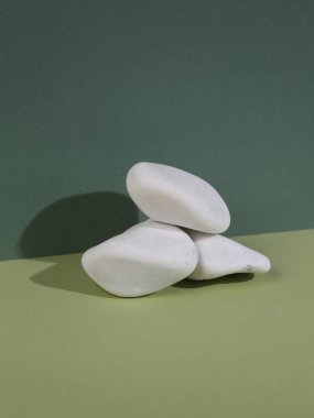 Minimalistic, aesthetic stage with white pebbles on two tone green background
