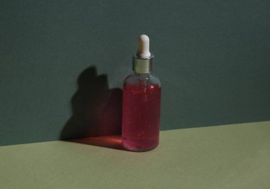 Aesthetic minimalist still life. Face serum bottle on two tone green background. Natural cosmetics, skin care
