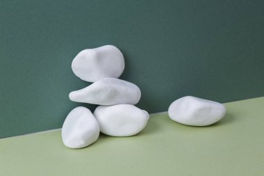 Aesthetic minimalistic still life. Pebbles on green background