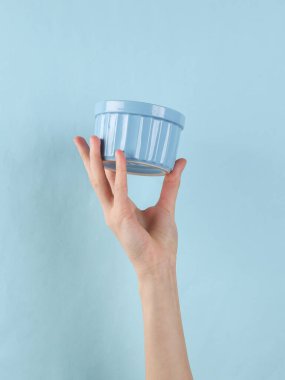 Blue ceramic bowl in female hand on a blue background.