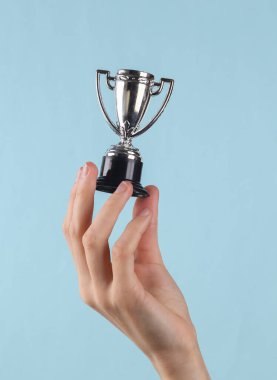 Mini goblet in female hand on a blue background.
