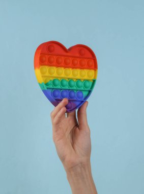 Pop it sensory antistress toy in female hand on a blue background.