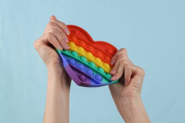 Pop it sensory antistress toy in female hands on a blue background.