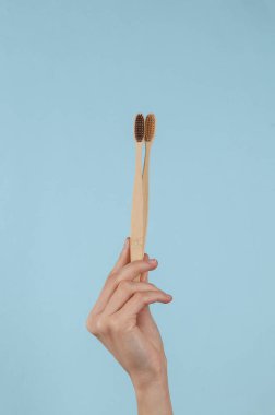 Eco Bamboo Toothbrushes in female hand on a blue background. Dental care