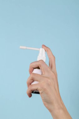 Throat spray in female hand on a blue background