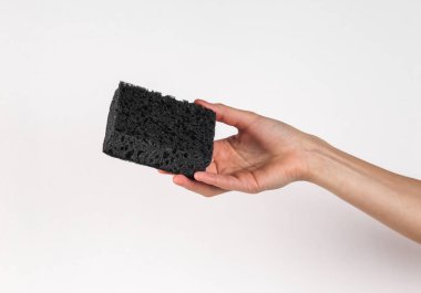 Black sponge in female hand on a white background