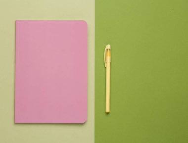 Cover of a pink notepad with pen on green background