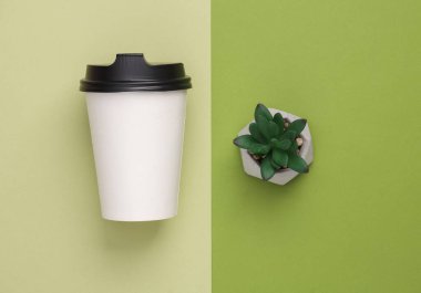 Mockup Blank Take Away Coffee Cup with decorative plant on green background