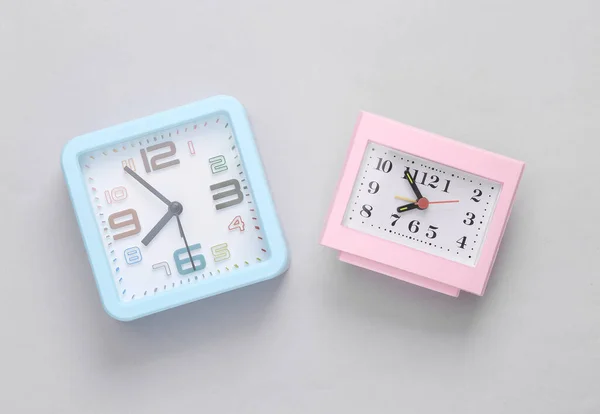 Two square clocks on a gray background. Top view