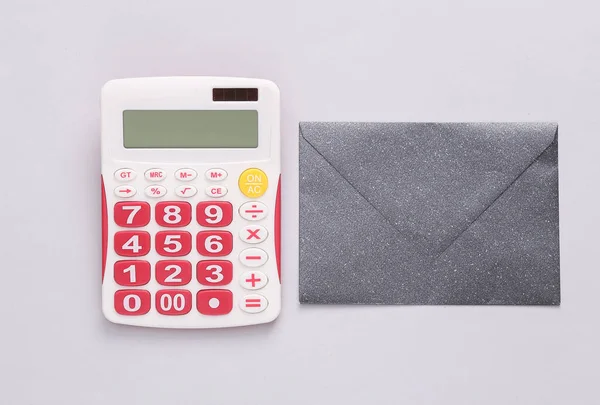 Payment of taxes, business concept. Calculator with envelope on gray background. Top view