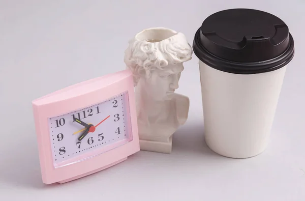 Coffee time, coffee break. Take away white cup and clock with David bust on gray background