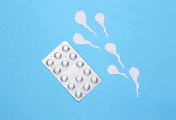 Birth control pills blister and male seed (spermatozoa) on a blue background. Contraception