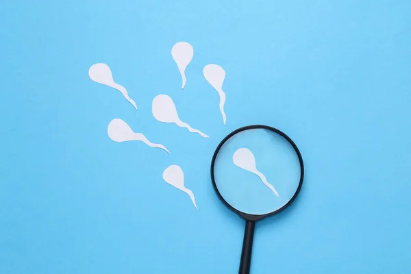 Diagnosis of male reproductive function. Spermatozoa, male seed with a magnifying glass on a blue background
