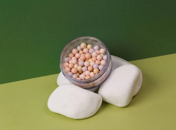 Aesthetic beauty or fashion still life. Powder balls box with stone on two tone green background. Natural cosmetics