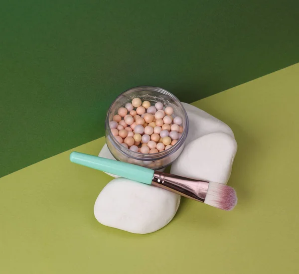 Aesthetic beauty or fashion still life. Powder balls box with makeup brush, stone on two tone green background. Natural cosmetics