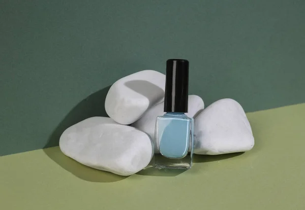 Aesthetic beauty or fashion still life. Nail polish -bottle with stone on two tone green background.