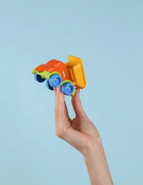 Toy dump truck in female hand on blue background.
