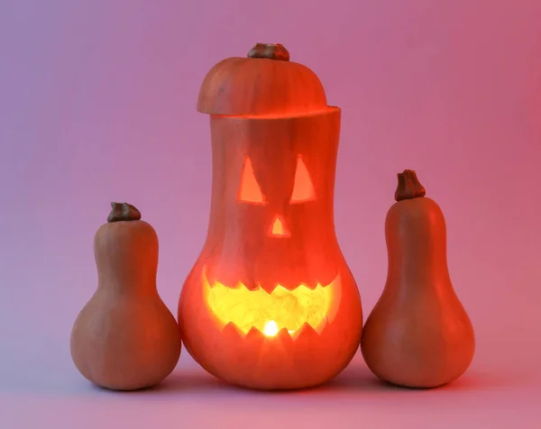 Glowing Halloween pumpkin in neon light. Scary glowing face, sinister smile. Minimal halloween still life. Trick or Treat